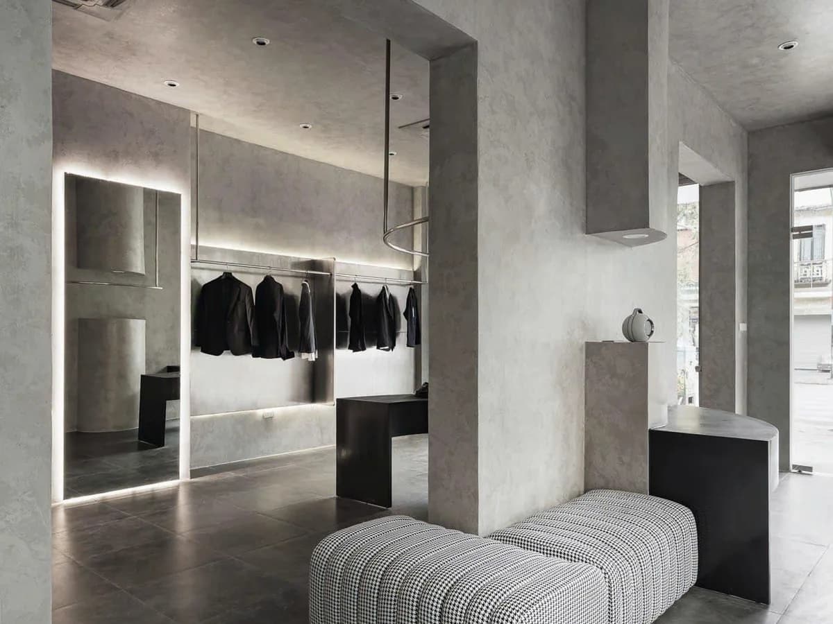 Không gian trưng bày với hốc tủ đèn, khu treo suit và ghế chờ tại showroom REMMY